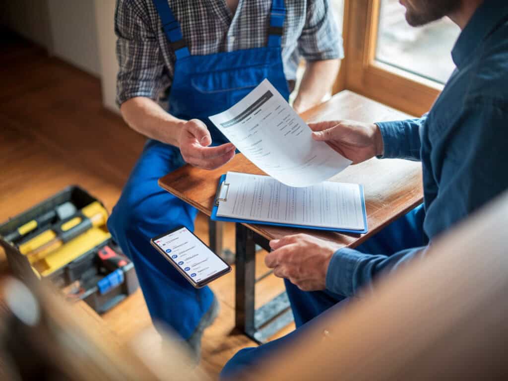 לקוח ובעל מקצוע יושבים יחד ומסתכלים על הצעת מחיר לפני תחילת עבודה